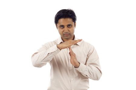 Serious looking young indian business man signaling time-outの写真素材