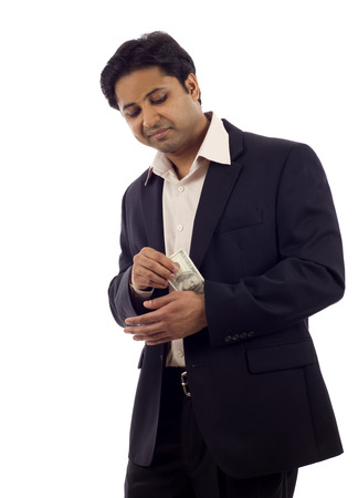 Indian Businessman pulling, hiding money from his sleeve isolated over white backgroundの写真素材