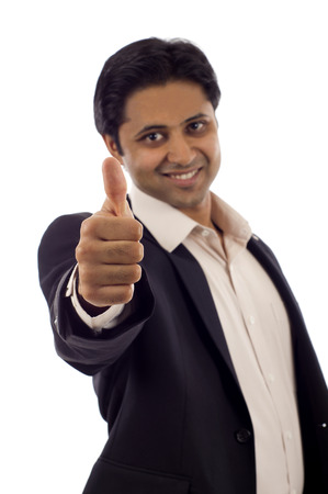 A handsome young Indian businessman showing thumbs up sign isolated over white backgroundの写真素材
