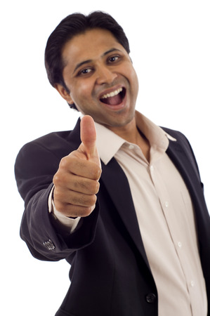 Happy young Indian businessman showing thumbs up sign isolated over white backgroundの写真素材