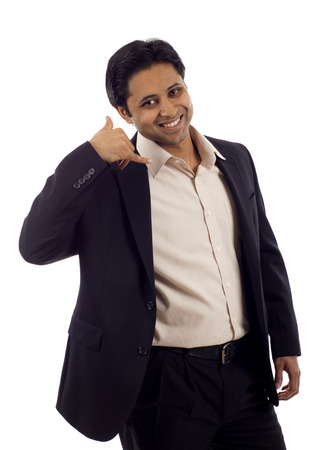 A handsome young Indian businessman giving call me gesture isolated over white backgroundの写真素材