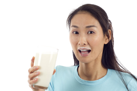 Healthy Asian woman drinking a glass of milk isolated over white backgroundの写真素材