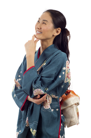 Beautiful thoughtful Japanese kimono woman looking up at copyspace isolated over white backgroundの写真素材