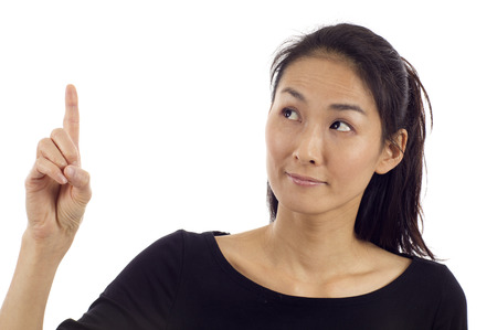 Beautiful Asian woman pointing up at copyspace isolated over white backgroundの写真素材