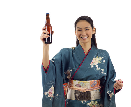 Happy excited Japanese kimono woman holding a bottle of beer with copyspace isolated over white backgroundの写真素材