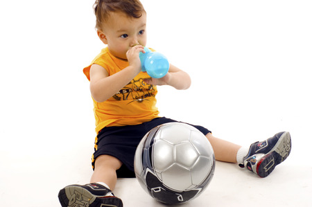 Adorable Baby Boy Drinking his Milk Bottle and Get himself Ready to Play Ball - Isolated over a white backgroundの写真素材