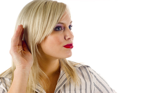 A Businesswoman Raises her Hand to her Ear to Listenの写真素材