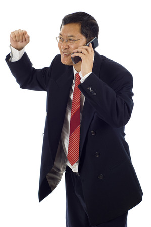 Isolated studio shot of a successful surprised Asian American businessman with clenched fist using mobile phone. Celebrating some happy newsの写真素材