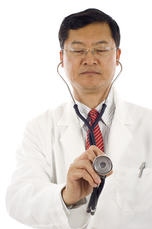Mature Asian doctor holding a stethoscope pointed toward camera. Hand and one part of stethoscope are in focus the rest of the image is out of focus.の写真素材