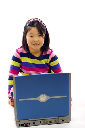 Adorable little Asian girl working on laptop , isolated over whiteの写真素材
