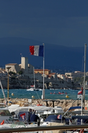 Antibes, France, August 31 2012, Torn French flag in windy conditions with the Picasso museum in the backgroundのeditorial素材