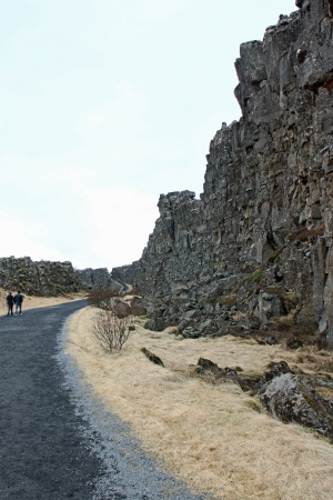 March 29th 2013, Thingvellir national park, Iceland, A pathway with two personas walking beside a wall of rocks on the right side.の写真素材