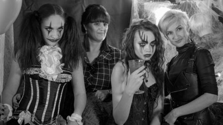 Portrait of women. Girl with a glass of red liquid. Bride of the devil in a wreath of red peonies. A clown with a smile in a corset.の写真素材