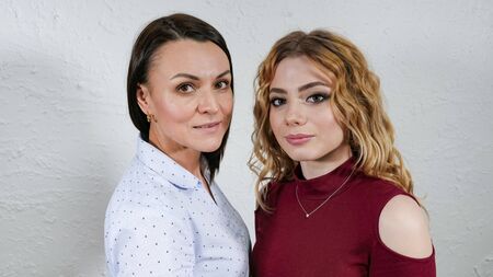 Blonde girl with curly hair and a brunette woman. Woman posing.