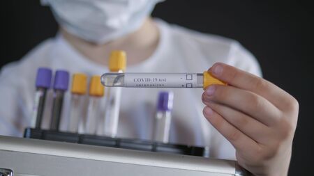 Boy is holding a metal suitcase. Child examines a medical test tube with a sample for the virus. Boy is careful of the virus. Pandemic March 2020. Coronavirus. COVID-19の写真素材