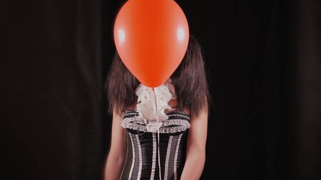 Easy Halloween Makeup. Girl with a red balloon, in the form of a clown. The ball disappears and reappears.の写真素材
