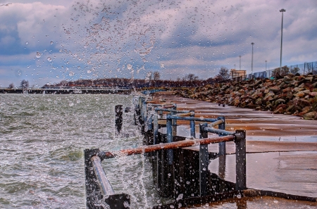 lake spray crashing over pier on choppy dayの写真素材