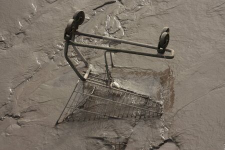 Shopping trolly in the mud, Thames river at low tide in East London, England, United Kingdomの写真素材