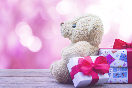 cute teddy bear and gift box  on wooden mock up over pink bokeh background with copy space,valentine's day concept.の写真素材