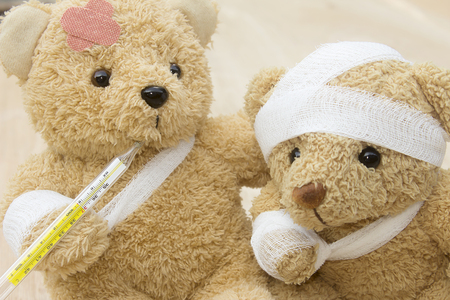 Teddy beas with bandages and thermometer on wood background with copy space.の写真素材