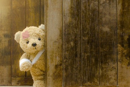 Teddy bear with bandages and broken hand on wood background,copy space.の写真素材