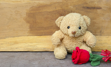 Valentine's day concept with Cute teddy bear and red rose in gift bag on wooden background for an anniversary or valentine's celebration.の写真素材