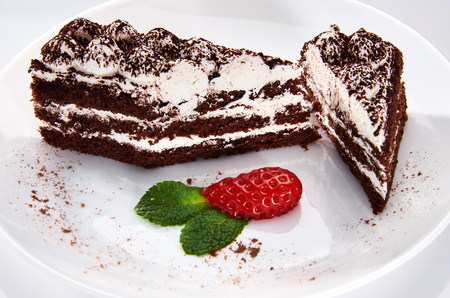 Chocolate cake on a white plate with strawberries and mintの写真素材