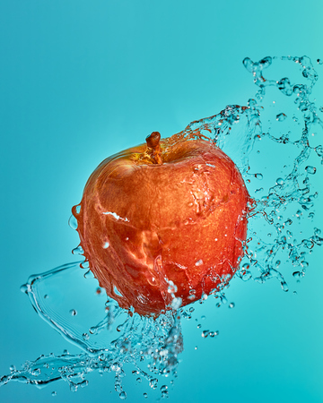 Red Apple in the flying spray of waterの写真素材