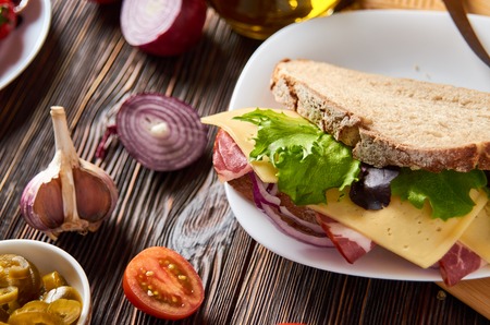 Sandwich with bacon, cheese, garlic, jalapeno pepper and herbs on a plateの写真素材