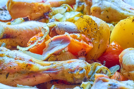 Baked roast chicken legs with tomatoes, onions, potatoes, mushroomsの写真素材
