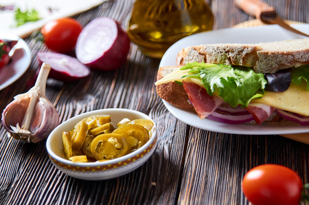 Sandwich with bacon, cheese, garlic, jalapeno pepper and herbs on a plate, on a wooden backgroundの写真素材