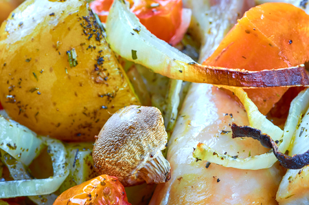 Baked roast chicken legs with tomatoes, onions, potatoes, mushroomsの写真素材