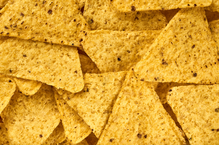 Background yellow triangular corn nachos with seasoningsの写真素材