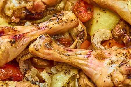 Baked roast chicken legs with tomatoes, onions, potatoes, mushroomsの写真素材
