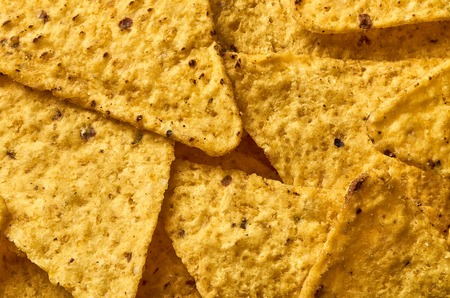 Background yellow triangular corn nachos with seasoningsの写真素材