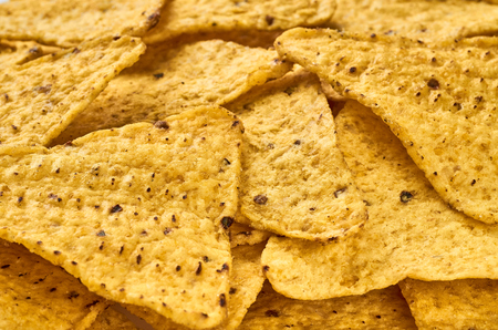 Background yellow triangular corn nachos with seasoningsの写真素材