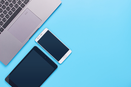top view upon gadgets on blue background, the composition of a laptop, headphones, phone, glass with a drink and car keysの写真素材