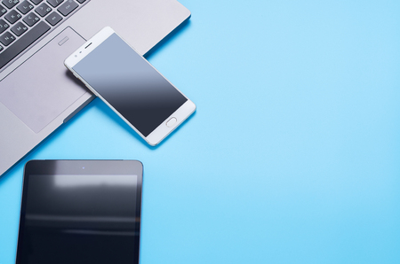 top view upon gadgets on blue background, the composition of a laptop, headphones, phone, glass with a drink and car keysの写真素材