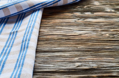 Old dark wooden background. Wooden table with blue kitchen towels in a cageの写真素材