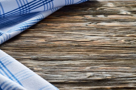 Old dark wooden background. Wooden table with blue kitchen towels in a cage