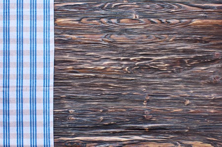 Old dark wooden background. Wooden table with blue kitchen towels in a cageの写真素材