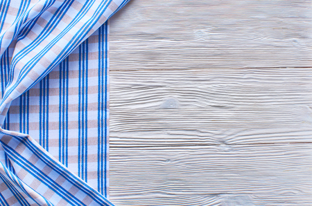 Old light wooden background. Wooden table with blue kitchen towels in a cageの写真素材