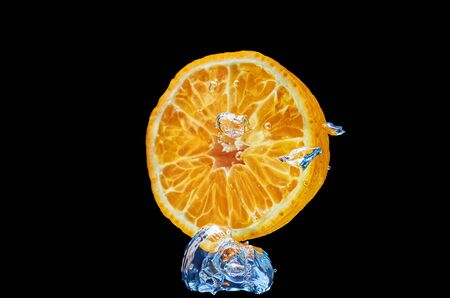 Fresh orange falling in water with splash on black background.の写真素材