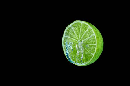 Fresh lyme falling in water with splash on black background.の写真素材