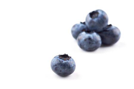 A group of blueberries on a white background, one blueberry berry in the foreground. Close up.の写真素材