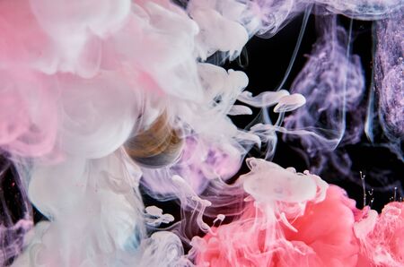 Pink and white acrylic inks in water on a black background surround the glass ball. Abstract...