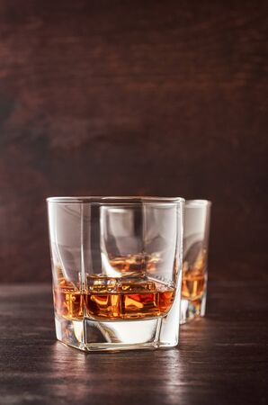 Two glasses of whisky with ice on a wooden table.の写真素材
