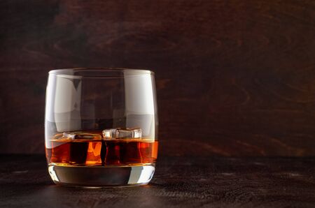A glass of whiskey with ice on a wooden tableの写真素材