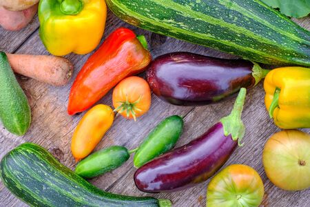 Still life of fruits and vegetables. Composition of zucchini, eggplant, tomatoes, cucumbers, peppers, carrots and potatoes. Vegetables are on an old wooden table.の写真素材