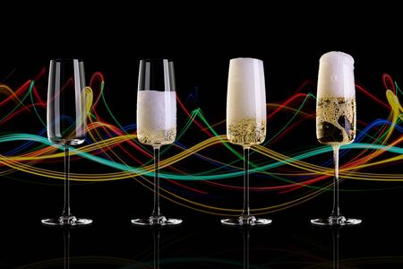 Four glasses of champagne on a black background with an abstract pattern. The empty glass, half glass, full glass, a glass with a large foam.の写真素材